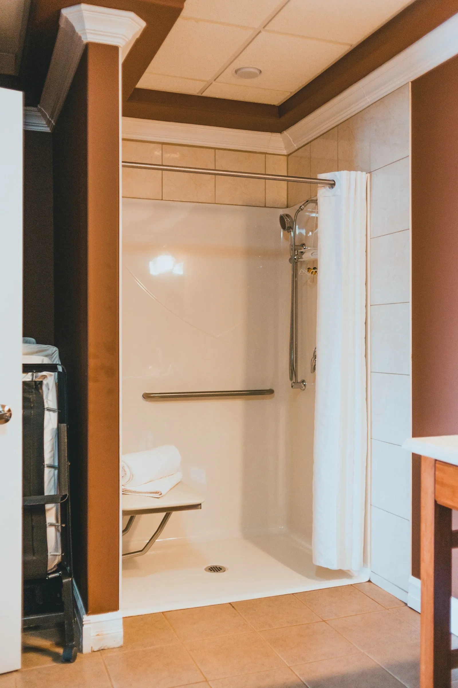 Roll-in accessible shower with a fold-down bench, grab bar and handheld sprayer