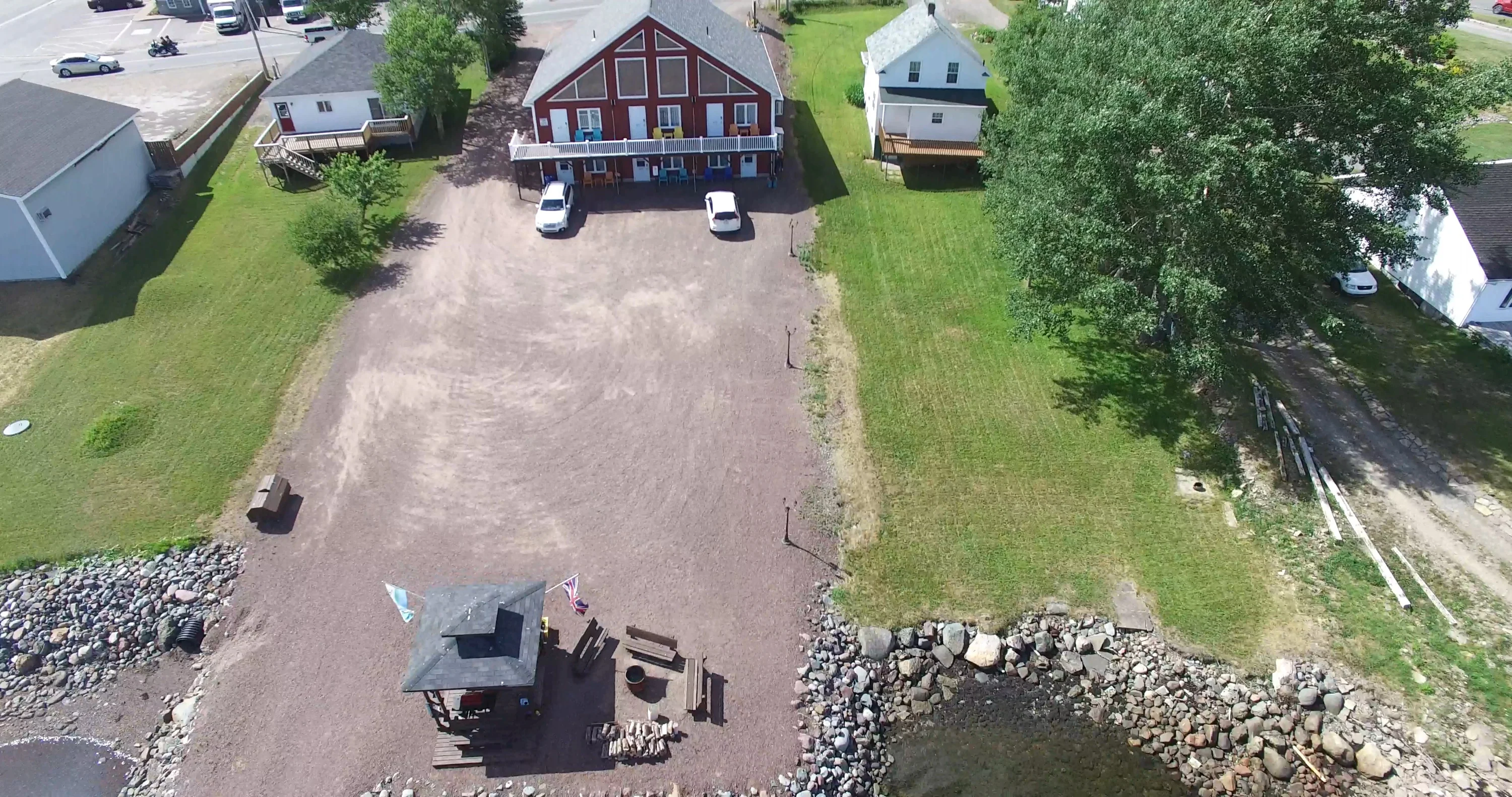 Aerial view looking down on the Islands' Villa grounds, showing the shoreline gazebo, the rocky beach and a private dock on the bay