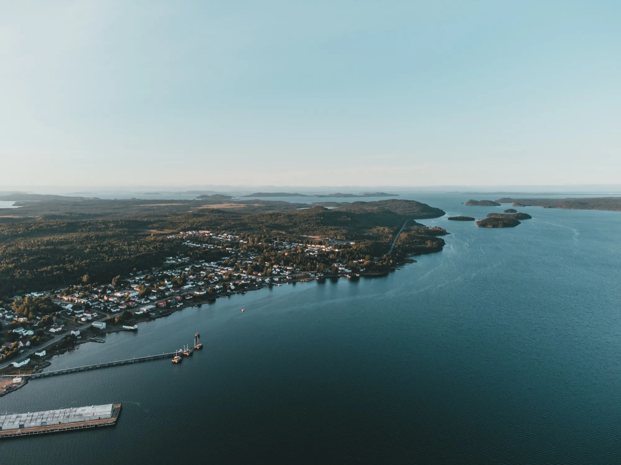 A wide aerial of the bay, its wooded islands and the long commercial wharf