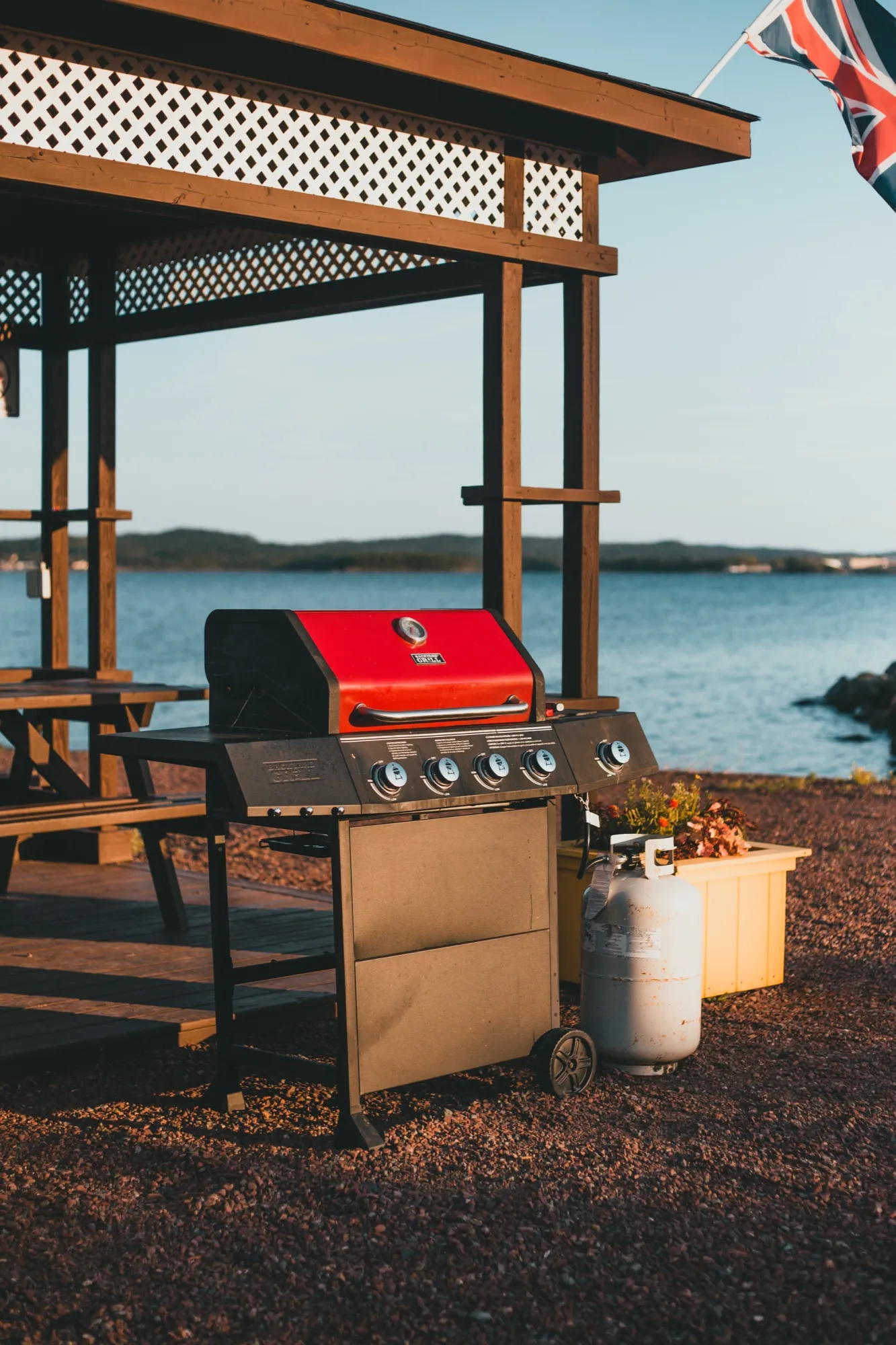 A propane barbecue and picnic tables under the gazebo, the bay and hills beyond