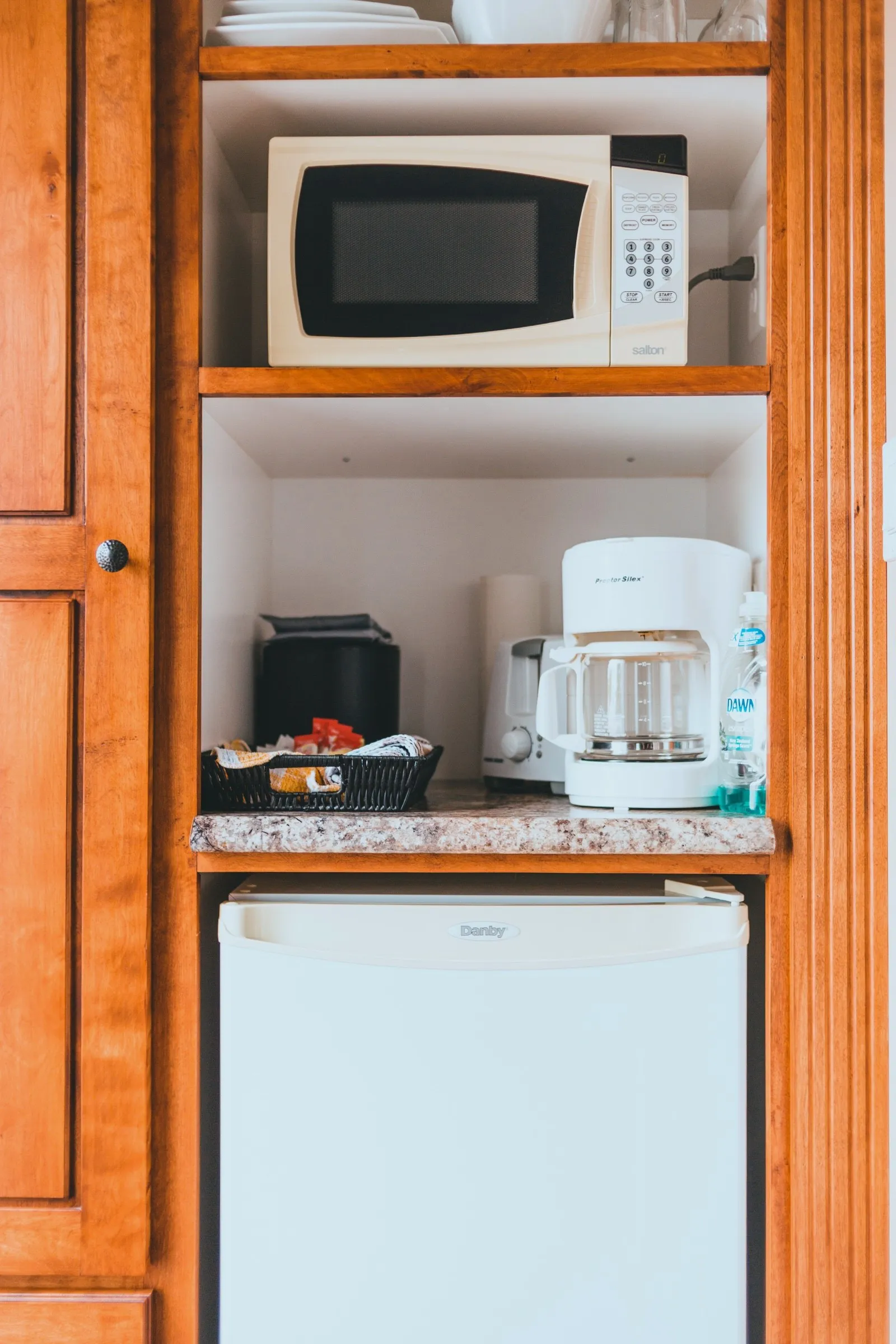 Built-in kitchenette cabinet in the Queen Room holding a microwave, coffee maker, toaster and mini fridge