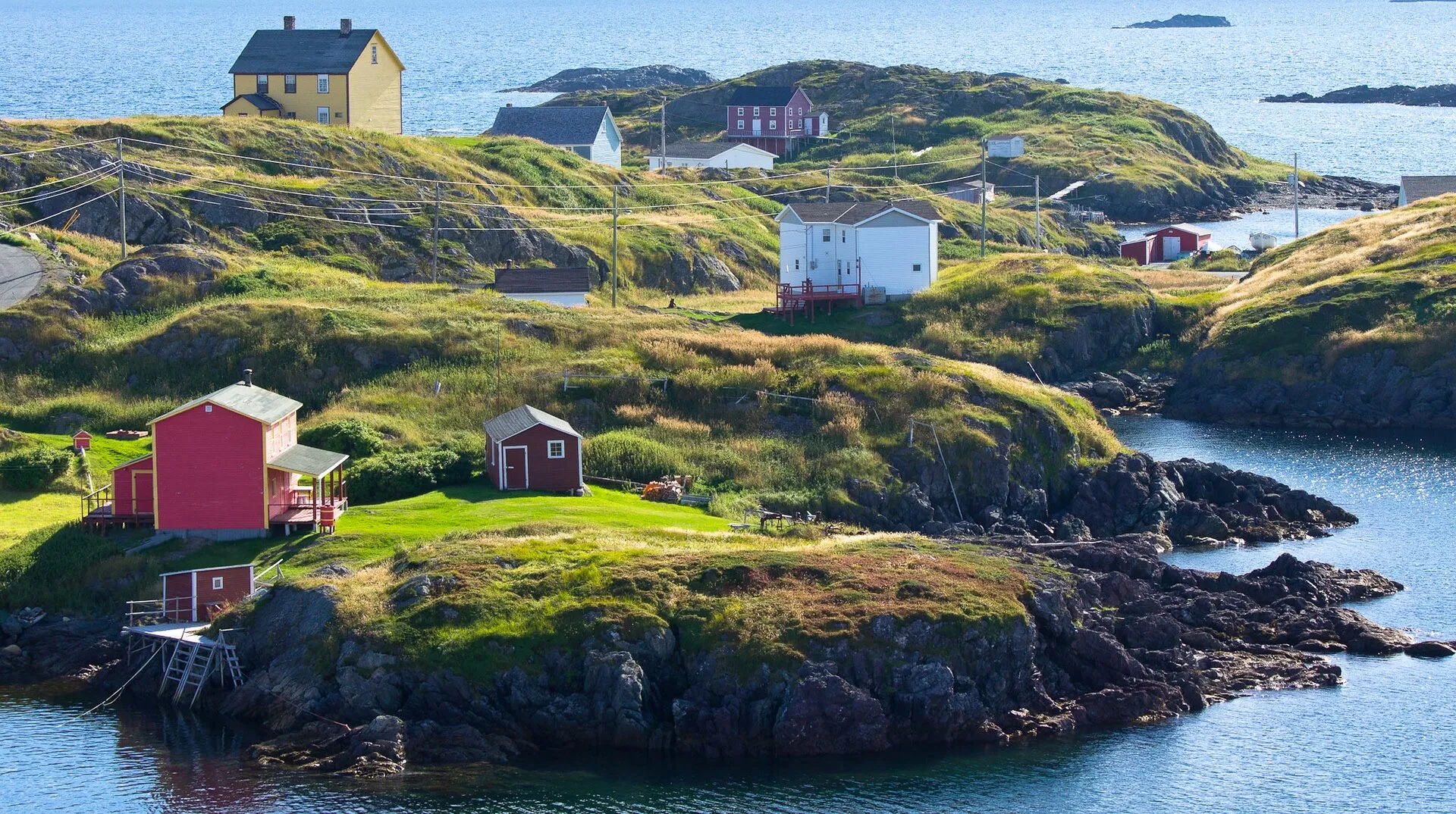 Saltbox houses and fishing stages scattered over green headlands on Change Islands, with the tickle winding between them.