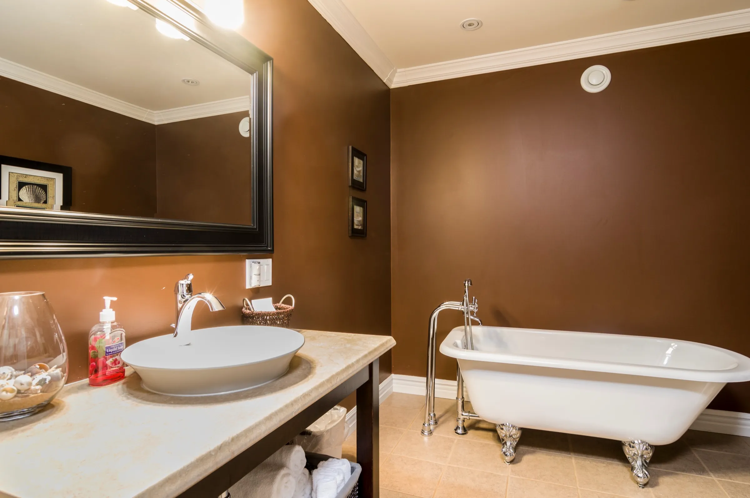 Freestanding clawfoot tub beside a vessel sink on a dark wood vanity
