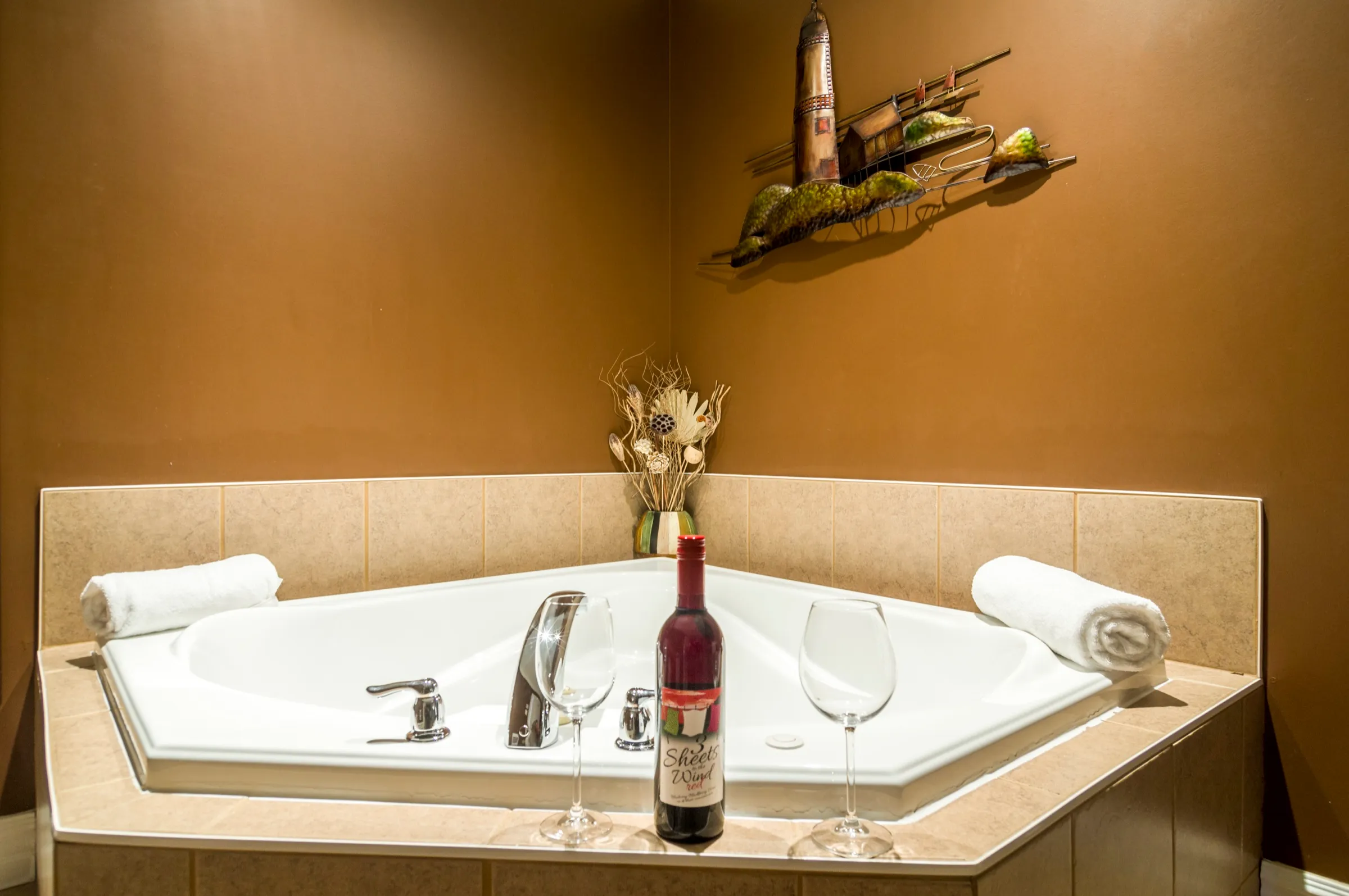 Corner jacuzzi tub set for two with wine and glasses on the surround