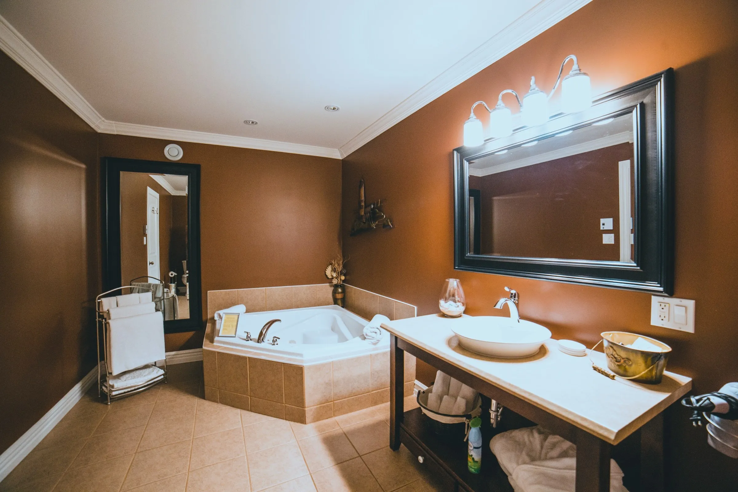 Ensuite bathroom with a corner jacuzzi tub, a vessel sink on a dark vanity and a large mirror