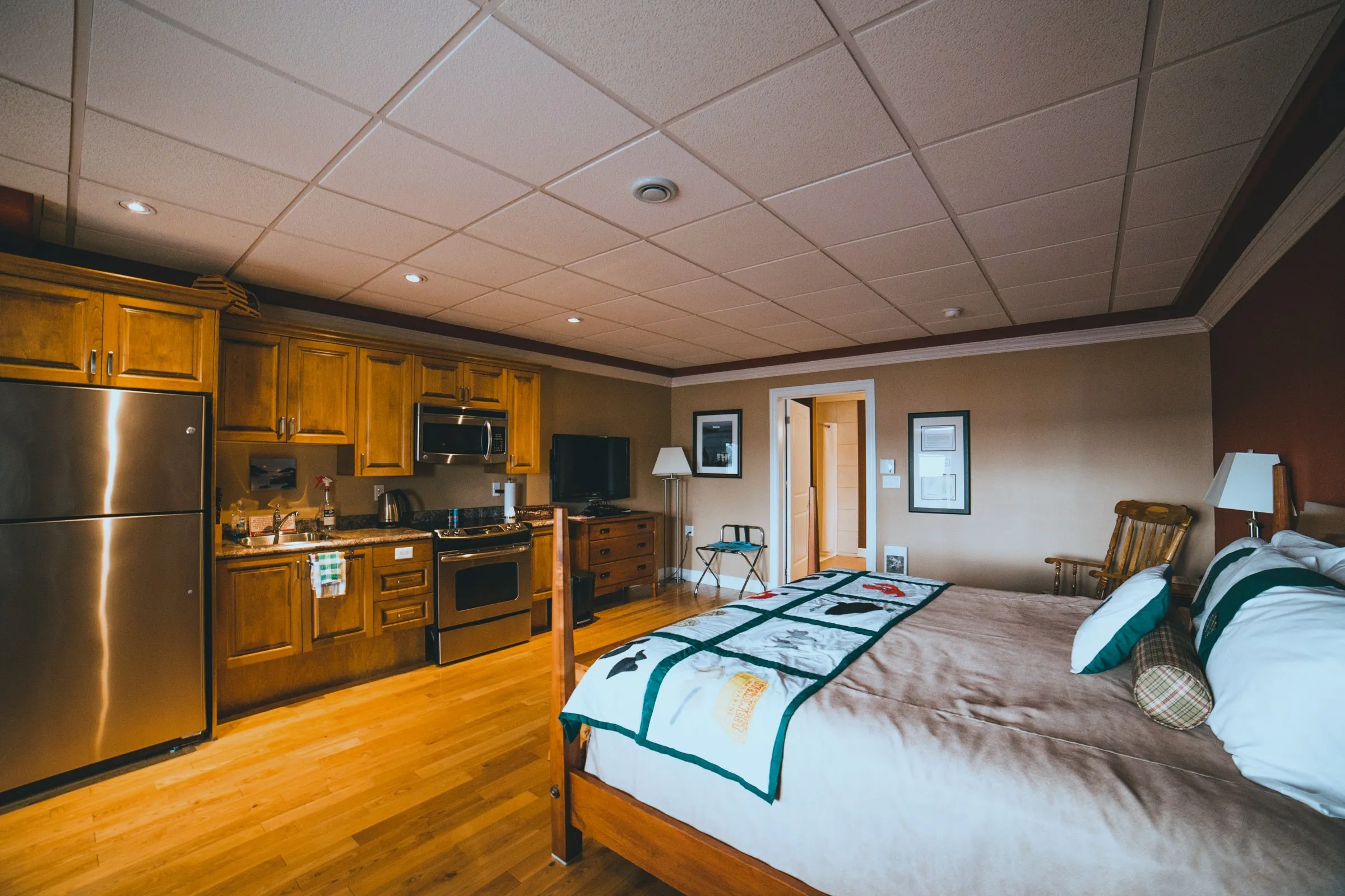 The King Suite full efficiency kitchen — stainless fridge, stove and microwave — with the king bed in the same open room