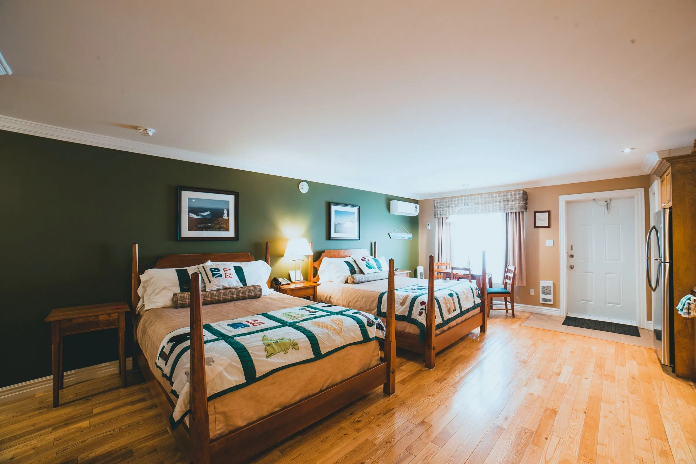 Two queen beds in the Family Suite beside a bright window, with the entry door and fridge to one side