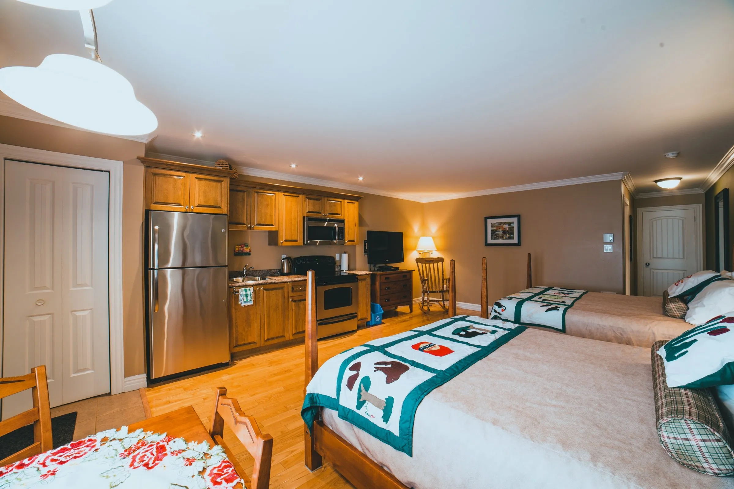 The Family Suite kitchen area with a stainless fridge, stove and microwave, looking back across the two queen beds