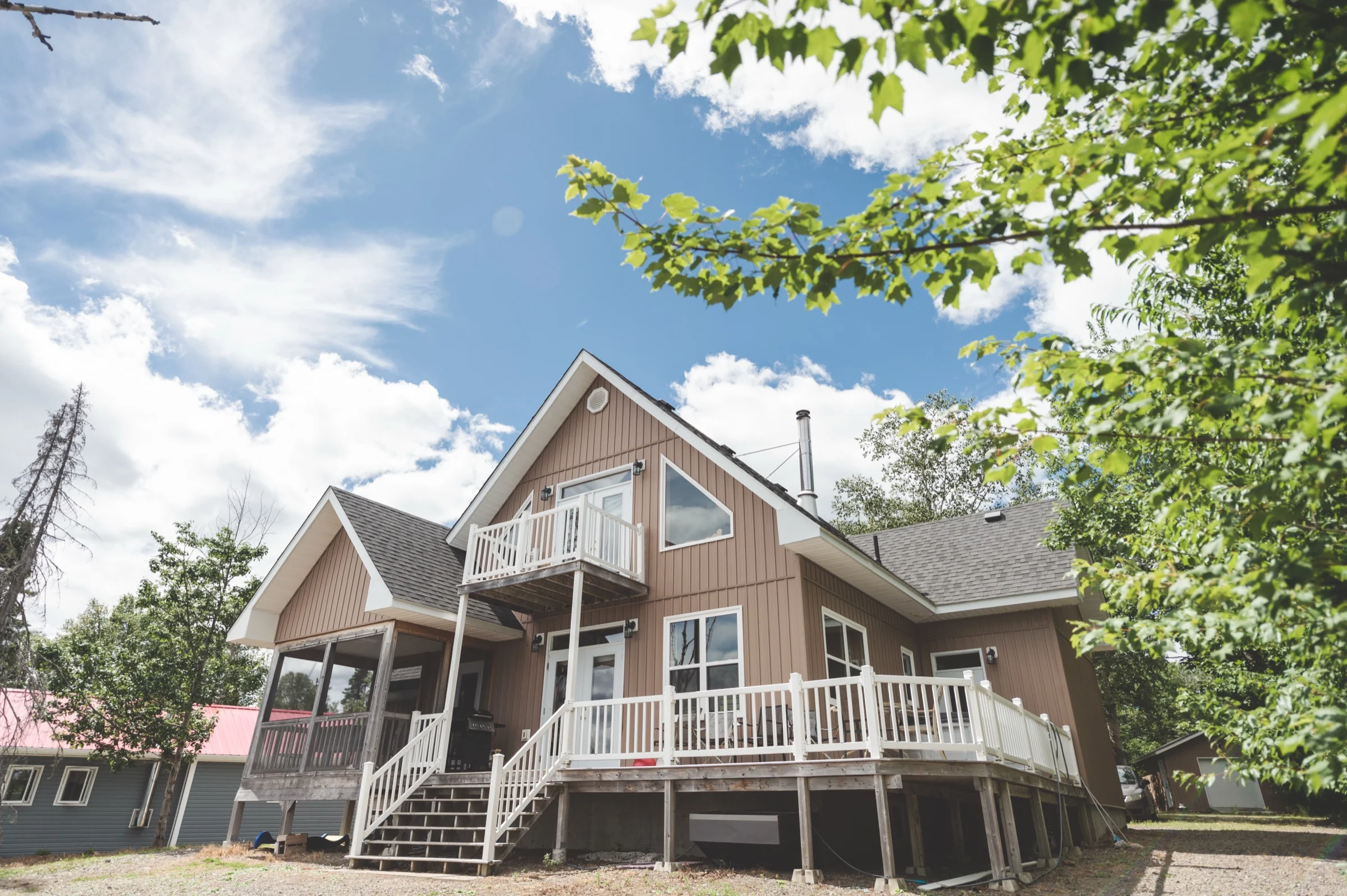 The Hideaway Chalet, a two-storey cabin with a wraparound balcony, set among spruce beside Monroe's Pond