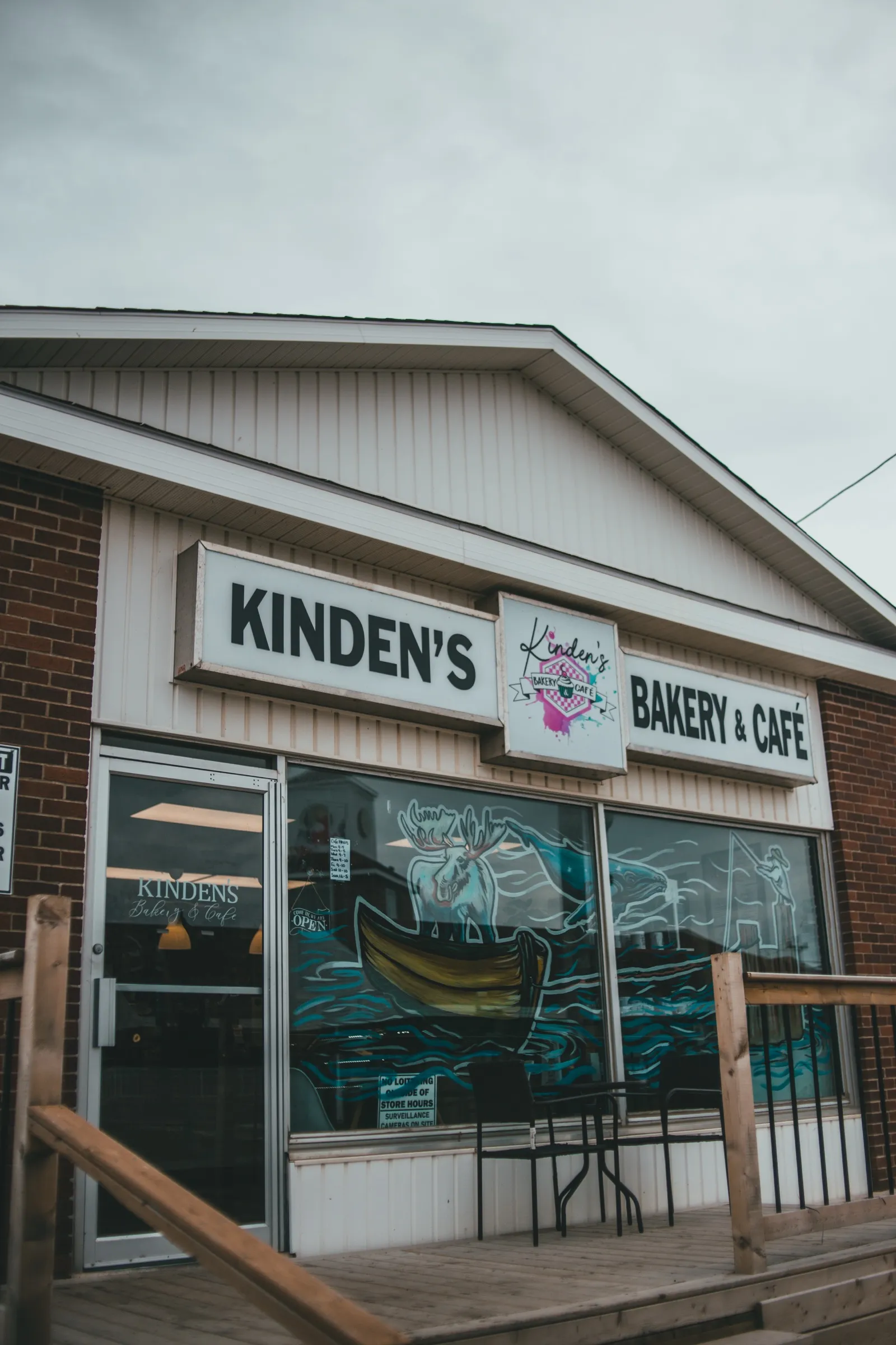 The storefront of Kinden's Bakery & Café, its windows painted with a moose in a canoe, a whale and an angler