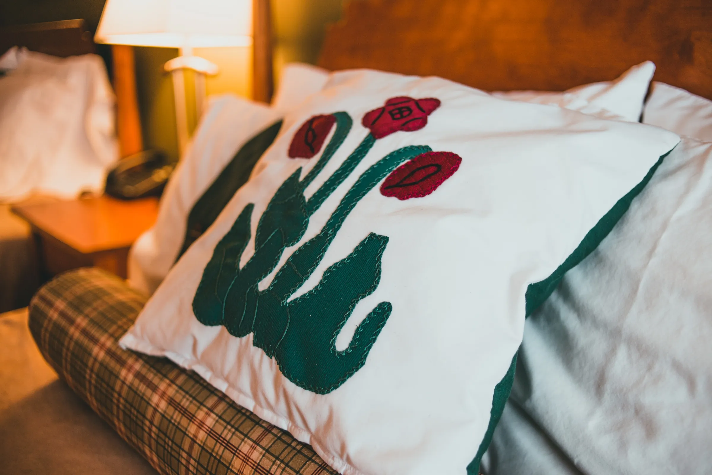 Close view of a white pillow with a hand-stitched pitcher plant appliqué
