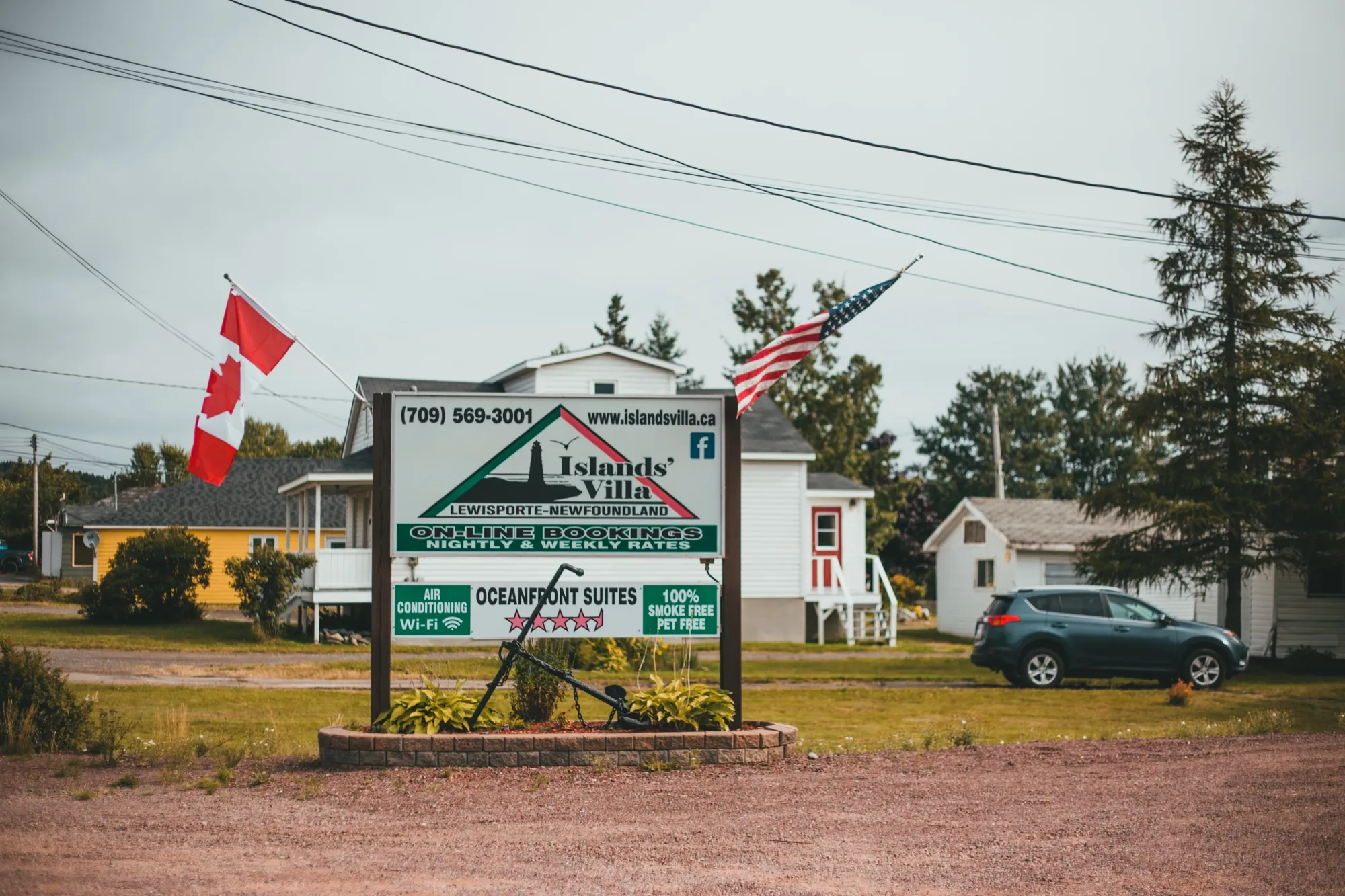 The Islands' Villa roadside sign advertising oceanfront suites, with Canadian and American flags flying beside it