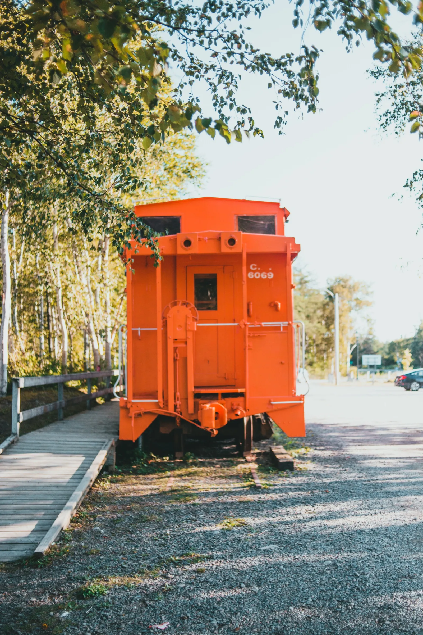 A restored orange Canadian National caboose, number 6069, on display beside a walking path