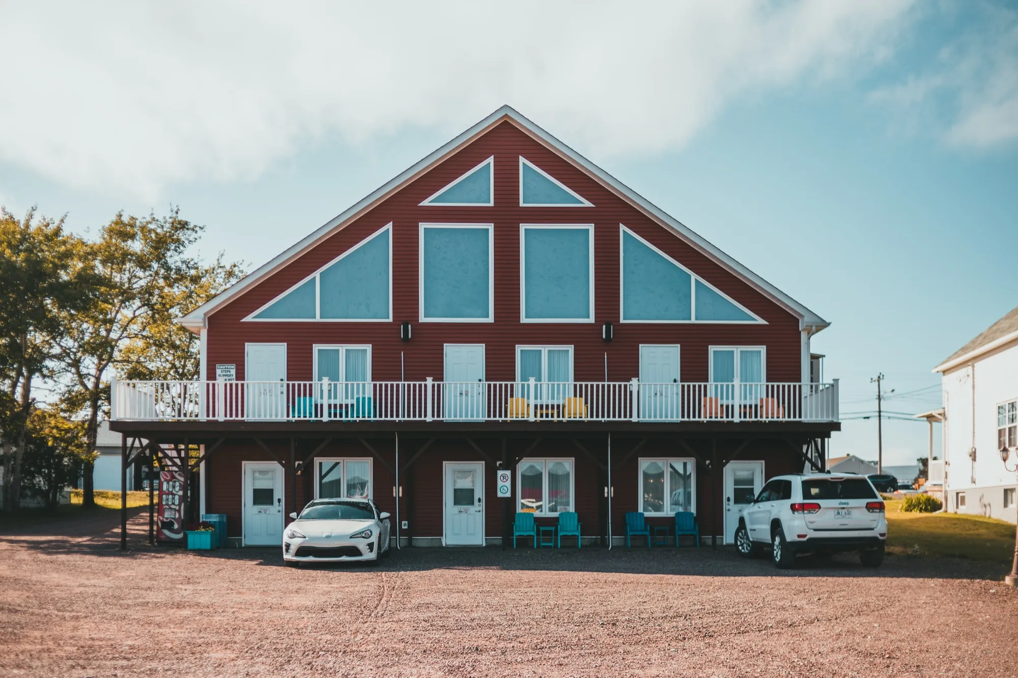 The red A-frame front of Islands' Villa under a blue sky, its balcony lined with bright Adirondack chairs